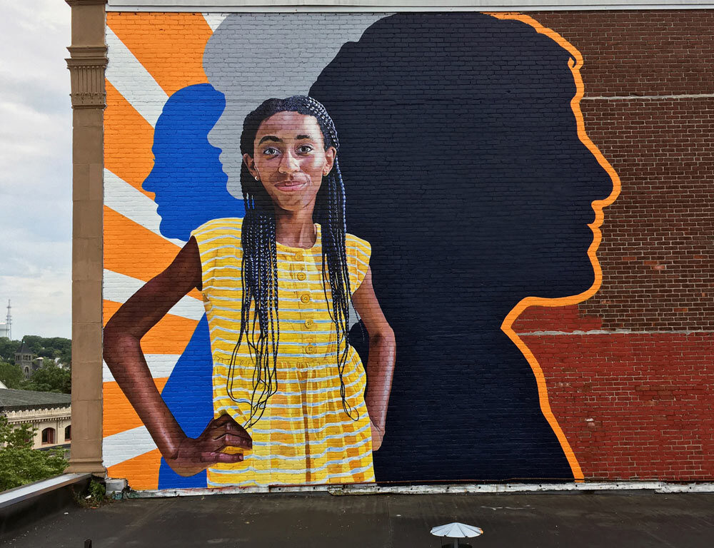 Fearless Girl Mural painted by Charles C. Clear III and Bonnie Lee Turner on the exterior of Beacon Carter School in Woonsocket, RI